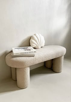 a white bench with a book on top of it next to a shell shaped object