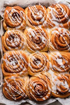 a pan filled with cinnamon rolls covered in icing