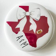 a button with a white bow on it that has the state of texas painted on it