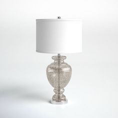 a lamp that is on top of a white surface with a light shade over it