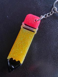 a yellow and red lighter keychain sitting on top of a black surface