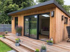 a small wooden shed with sliding glass doors and patio furniture on the decking area