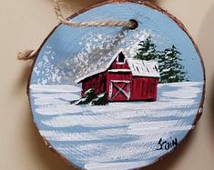 a painted christmas ornament with a barn in the snow on it's side