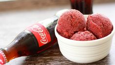 red velvet cookies in a white bowl next to a coca - cola bottle