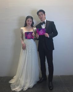 a man and woman standing next to each other holding up their book's covers