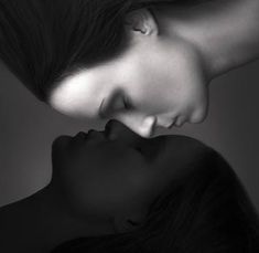 two women are touching each other with their heads close to one another in black and white