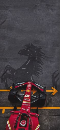 a ferrari racing car parked in front of a horse drawn shadow on the pavement,