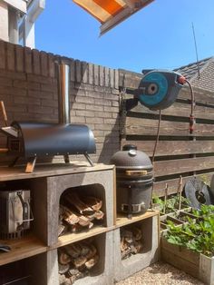 an outdoor bbq grill with wood stacked in it and a pizza oven on top