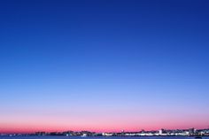 the sky is pink and blue as the sun sets in the distance over water with buildings on both sides