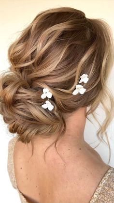 a woman with her hair in a low bun and two flower clips on the back of her head