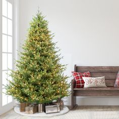 a small christmas tree sitting next to a wooden bench in a room with white walls