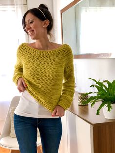 a woman standing in front of a mirror wearing a yellow knitted sweater and jeans