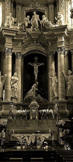 an ornate church with statues on the front and side walls, including a crucifix