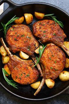 pork chops and potatoes in a cast iron skillet with rosemary garnish