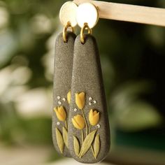 two earrings with yellow flowers on them hanging from a clothes line