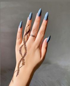 a woman's hand with blue nail polish and an intricate design on her wrist