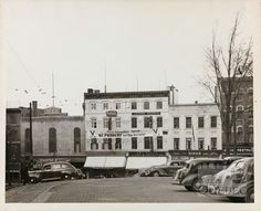 an old black and white photo of cars parked in front of buildings