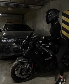 a woman sitting on the back of a motorcycle in a parking garage next to a car