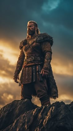 a man dressed in medieval clothing standing on top of a hill with clouds behind him