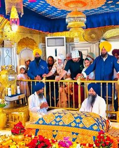 a group of people standing around a bed in a room filled with gold and blue decorations