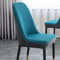 two blue chairs sitting next to each other in front of a window with drapes