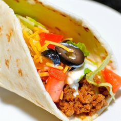 a burrito filled with meat and vegetables on a white plate