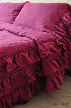 a bed with pink sheets and ruffled bedspread