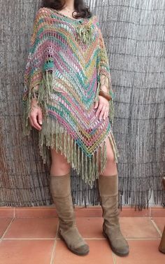 a woman standing in front of a wall wearing a colorful poncho and boots