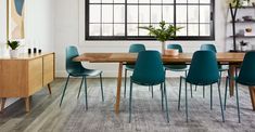 a dining room table with blue chairs in front of a large window and potted plant