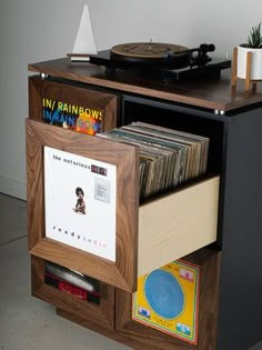 a record player is sitting on top of a wooden cabinet with records and cds in it