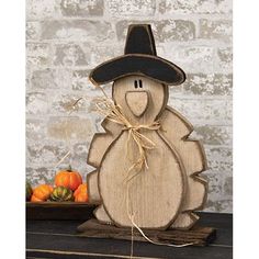 a wooden turkey with a black hat on it's head sitting next to some pumpkins