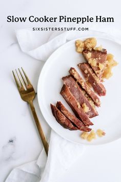 a white plate topped with sliced meat next to a fork