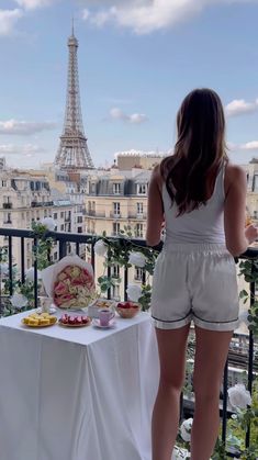 a woman standing on a balcony overlooking the eiffel tower