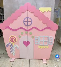 a pink wooden toy house with candy land on the front and side doors that are cut out to look like it is made from cardboard