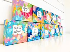 three colorful boxes with writing on them sitting next to each other in front of a white wall