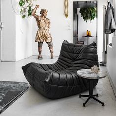 a living room with black leather furniture and a plant in the middle of the room