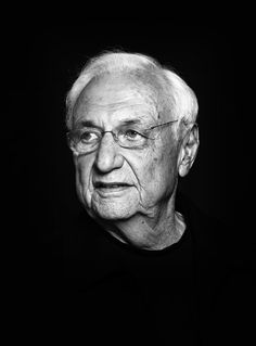 black and white photograph of an old man with glasses looking off to the side in front of a dark background