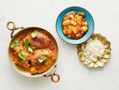 two bowls filled with food on top of a white table next to other foods and utensils