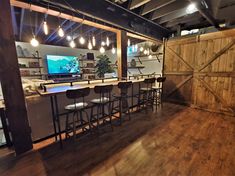 a bar with stools in front of it and a flat screen tv on the wall