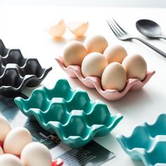 several eggs in trays next to spoons and forks