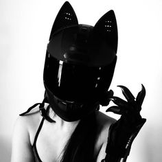 a woman wearing a cat mask and holding a black glove up to her face with one hand