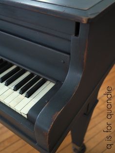 an old piano with black and white keys on the wood floored area in front of it