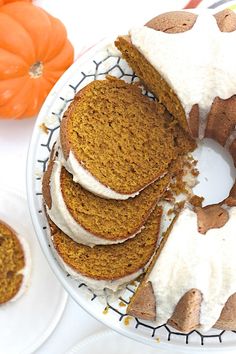 a cake with white frosting and pumpkins in the background on a plate next to it