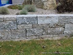 a stone wall with grass and rocks in the background