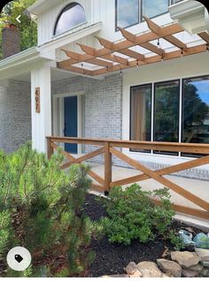 a house that has a wooden fence in front of it and some plants on the ground