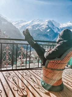 a person sitting in a chair on top of a wooden deck next to a mountain