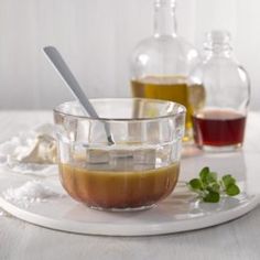 a glass bowl filled with liquid sitting on top of a white plate next to bottles