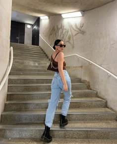 a woman standing on some stairs with her hands in her pockets