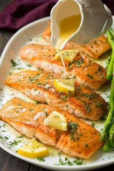 salmon and asparagus on a white plate being drizzled with lemon