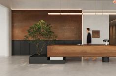 a person walking past a desk with a plant in front of it on the floor